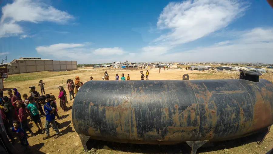 Families with containers beside a large water tank