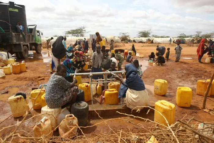 People collecting water in containers at a communal water point