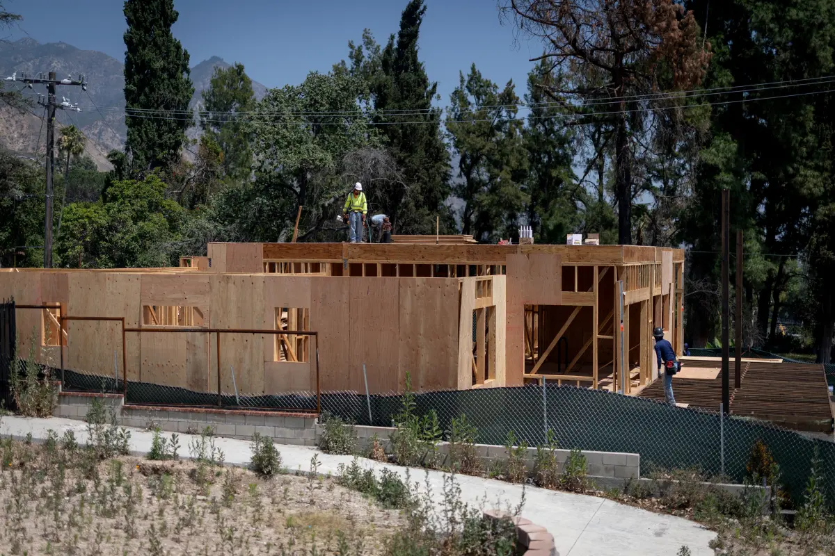 Workers at the timber frame of a home under construction on Palm Street in Altadena