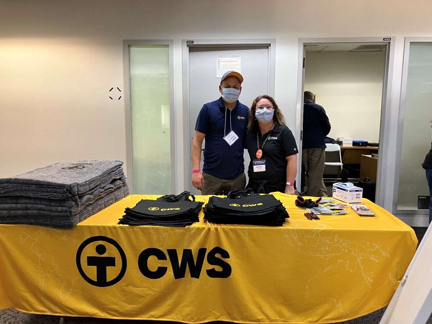 A CWS relief table with folded blankets and branded supply bags