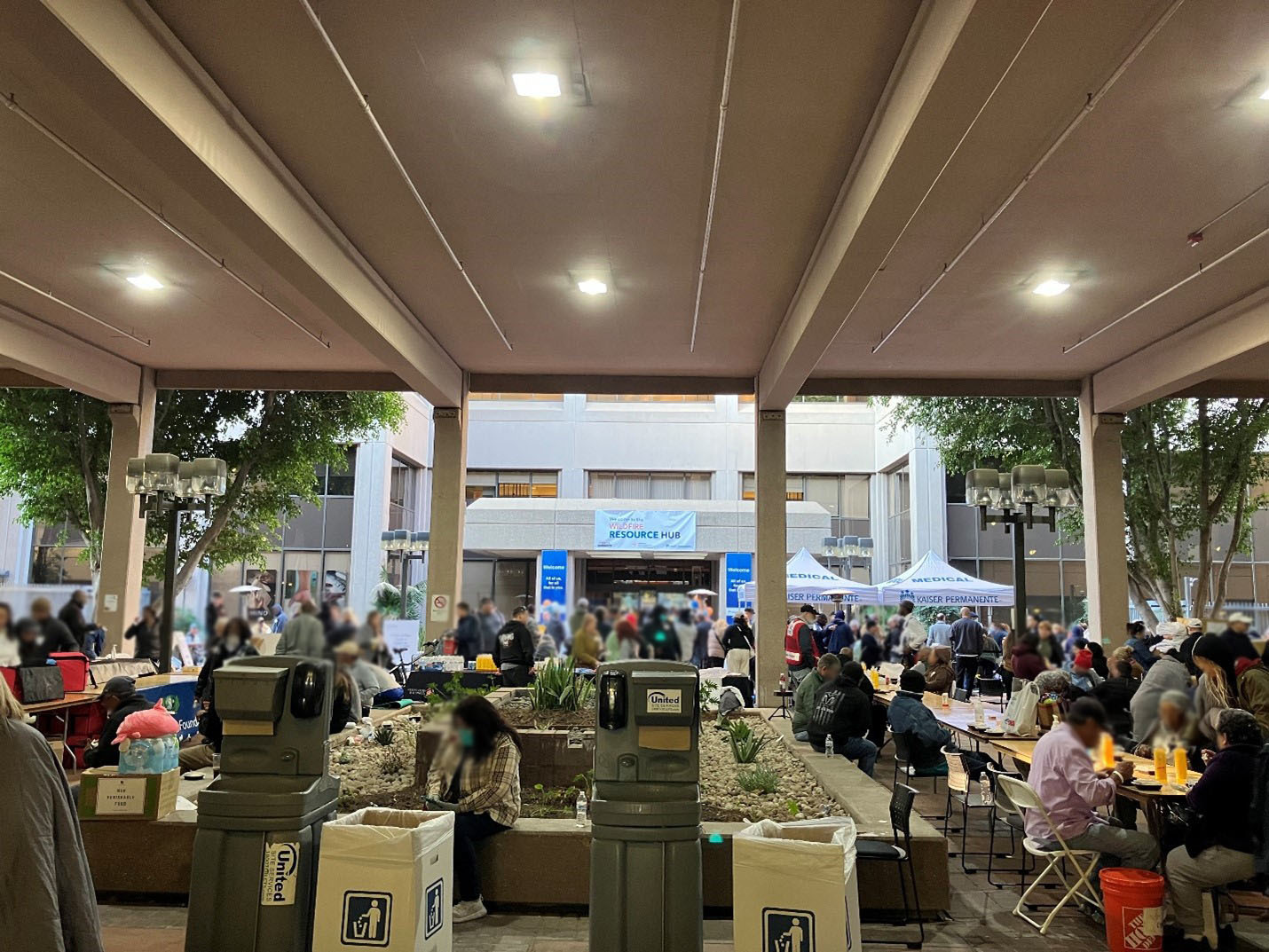 People and service tables in a courtyard beneath a Wildfire Resource Hub banner